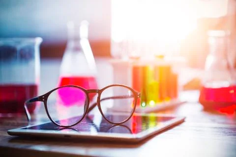Glasses on tablet screen with blurred science equipments on background. Educa Stock Photos