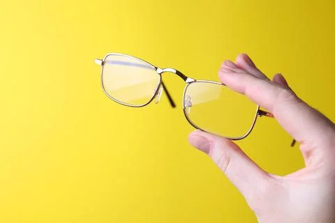 Glasses for vision correction in the hand on a colored background with space for Stock Photos