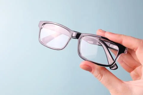 Glasses for vision correction in the hand on a colored background with space for Stock Photos