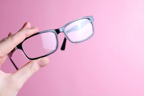 Glasses for vision correction in the hand on a colored background with space for Foto stock