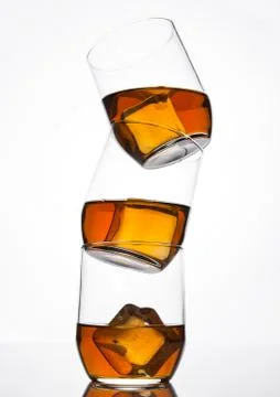Glasses of whiskey with ice cubes with reflection on white background Stock Photos