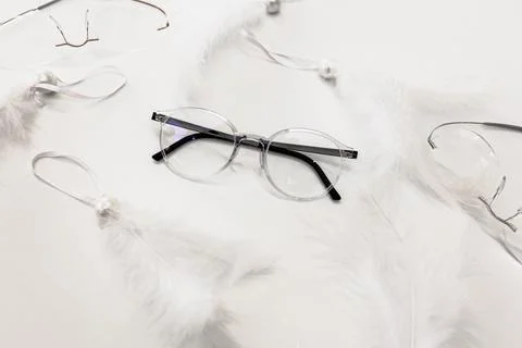 Glasses on a white table surrounded by feathers Stock Photos