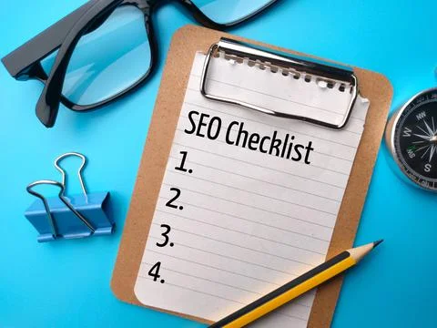 Glasses,pencil,compass and paper clips with text SEO Checklist on blue backgr Stock Photos