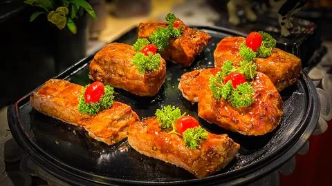 Glazed beef with herbs and tomatoes on a black tray Stock Photos