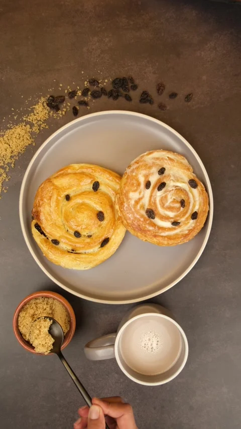 Glazed cinnamon roll, placing a spoonful of muscovado sugar in a cup of coffee Stock Footage 279355117
