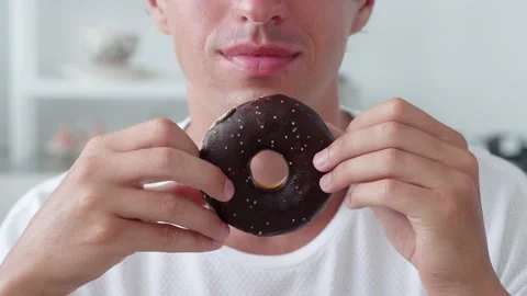 Glazed donut with chocolate on man hands. Maile biting a cake Stock Footage 175163580