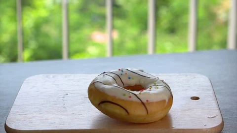 Glazed Donut Falling Down on Wooden Tray on Table Stock Footage 105782793
