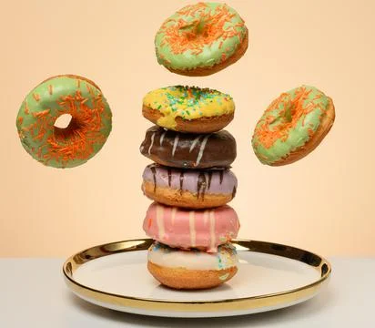 Glazed donuts, each decorated with multi colored sprinkles. Sweets levitate.. Stock Photos