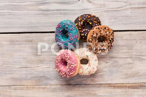 Glazed donuts with sprinkles on a white wooden table Stock Photos