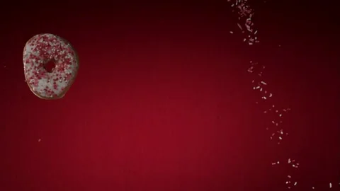 Glazed pink heart donut falling through a red background Stock Footage 327788771