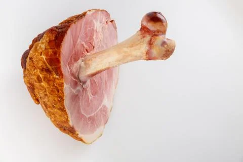 Glazed pork ham with big bone on white isolated background. Stock Photos