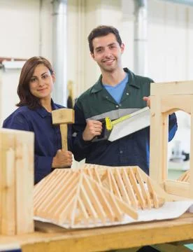 Gleeful trainee and instructor standing behind construction Stock Photos