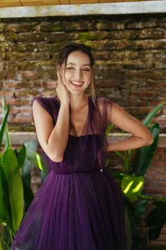 Gleefully laughs baring the even teeth of a edged young woman against a wall and Stock Photos