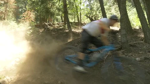 Glide cam shot of two guys on mountain bikes taking a turn and making dirt fly. Video stock 77581528