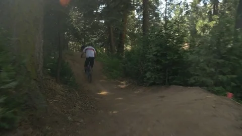 Glide cam shot of two guys mountain biking on a  wooden wall ride. Video stock 77585856