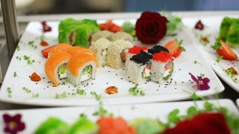 Glide panorama of assorted sushi sets decorated with romantic rose and greenery Video stock 98777708