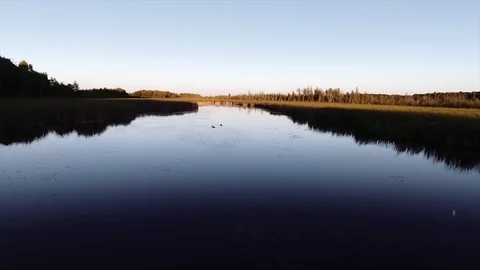 Gliding across a small pond during sunset - Aerial drone shot Stock Footage 115351965