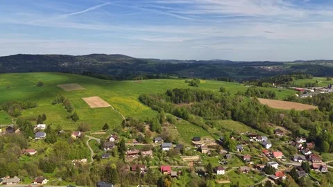 Gliding aerial view over rolling green hills, patchwork farmland, winding roads, Stock Footage 342355450