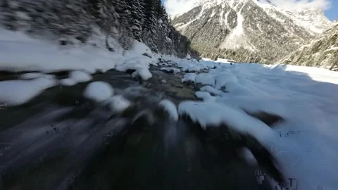 Gliding along a snowy river in a mountain valley Stock Footage 314417853