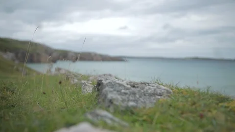 Gliding Beach cliff top grass and rocks with the sea in the background Stock-Footage 106914041