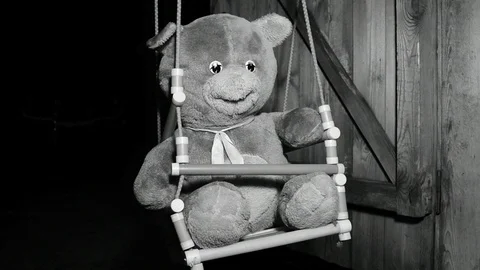 Gliding beam of light quickly illuminates a teddy bear, black and white Stock Footage 120247037