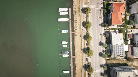 Gliding drone top-down over Grado marina boats and waterfront road 4K 動画素材 331171666