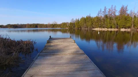 Gliding off end of dock, out over pristine lake into wilderness Stock Footage