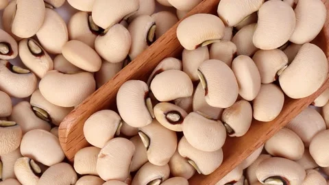 Gliding panning zoom out over Blackeye beans in wooden scoop spoon top view on w Stock Footage 228847149