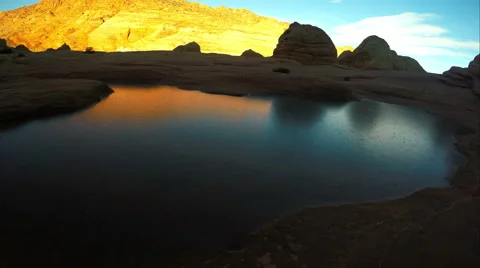Gliding view over a frozen pool of water as the sun lights up the cliffs. Video stock 54055891