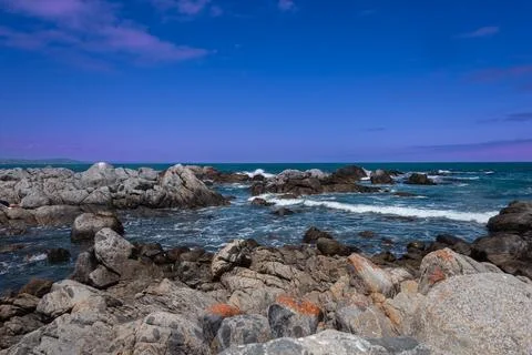 A glimpse of the Pacific Ocean in central Chile with rocks and pink clouds. Stock Photos