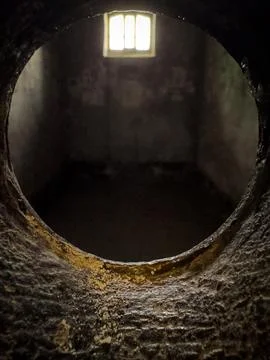 A glimpse into a prison cell through a small, circular opening Stock Photos