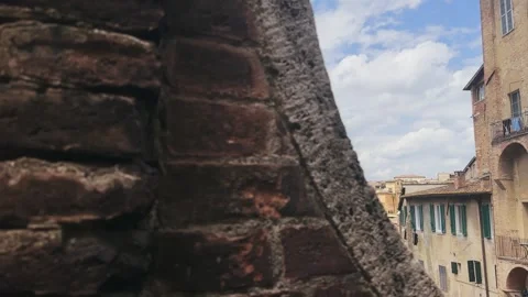 Glimpse through aged brick wall revealing Siena landmark basilica Catariniana Stock Footage 345150792