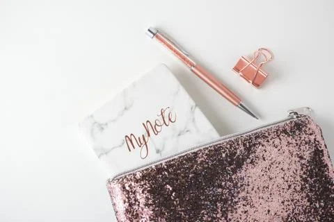 Glitter bag with pen, planner notebook, pink gold accessories on white desk b Stock Photos