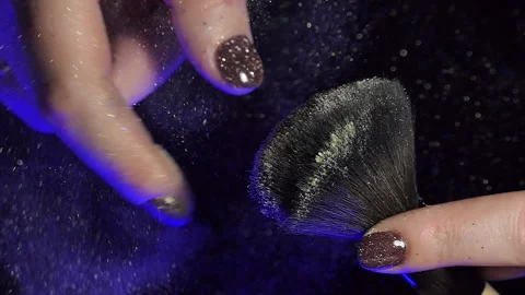 Glitter on makeup brush flying away with woman snapping her finger in slow Stock Footage 228432931
