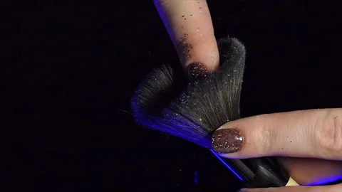 Glitter on makeup brush flying away with woman snapping her finger in slow Stock Footage 228690767