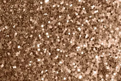 Glittering bronze texture with hexagonal sequins under soft illumination Stock Photos