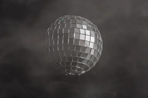 A glittering disco ball against a dramatic black backdrop with smoke, evoki.. Stock Photos