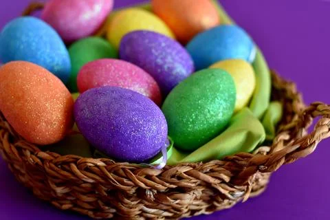 Glittering easter eggs in a wicker basket nest Photos