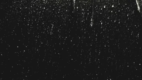 Glittering white particles falling downward against dark black background Stock Footage 340941705