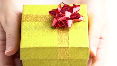 Glittering yellow gift box, close up. Hands put a golden gift box on the ta.. Stock Footage 254887464