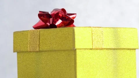 Glittering yellow gift box with a red bow rotates. Birthday or Christmas co.. Stock Footage 254326146
