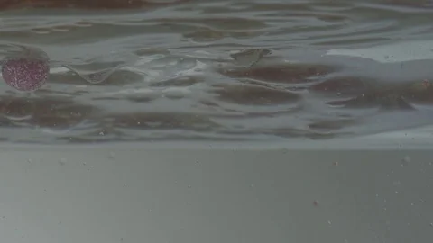 Glittery peach and gold bubbles sink in water Stock Footage 77778769