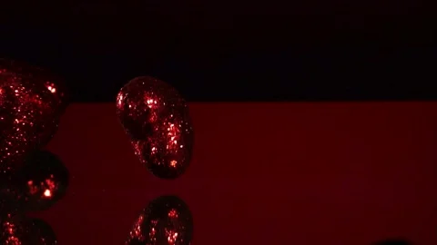 Glittery red hearts fall on red surface Stock Footage 327180378