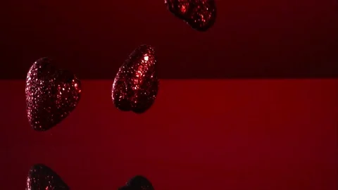 Glittery red hearts falling on red surface Stock Footage 327051144