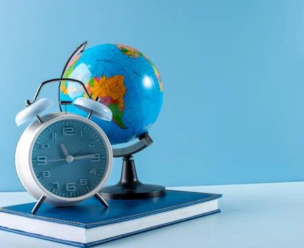 Globe alarm clock and notebook on blue background Stock Photos