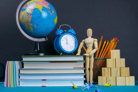 The globe and the clock stand on a stack of books, next to a glass of pencils Stock Photos