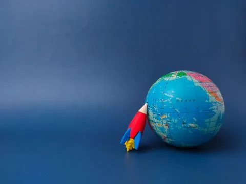 Globe and a small red and blue toy rocket. The rocket is positioned on the .. Stock Photos