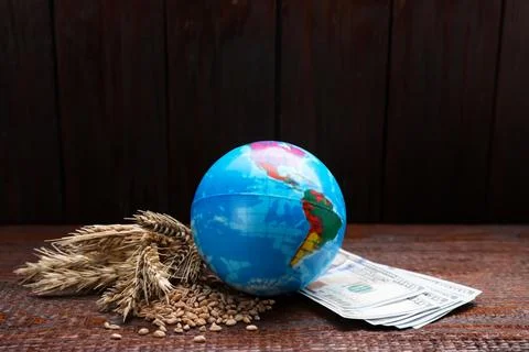 Globe, ears of wheat and banknotes on wooden table. Import and export concept Stock Photos