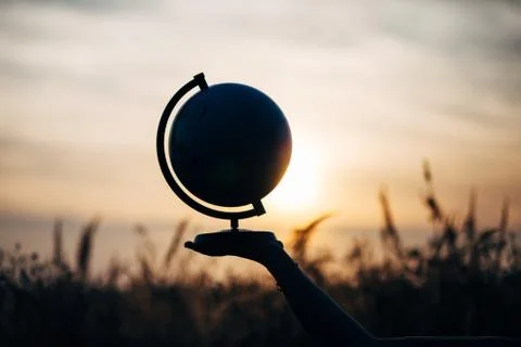 Globe on hand at sunset in the field Stock Photos
