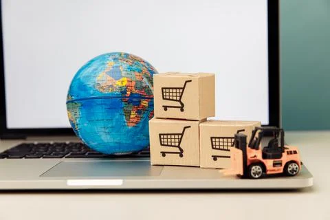 Globe model with boxes on a laptop. Online shopping and delivery concept Stock Photos